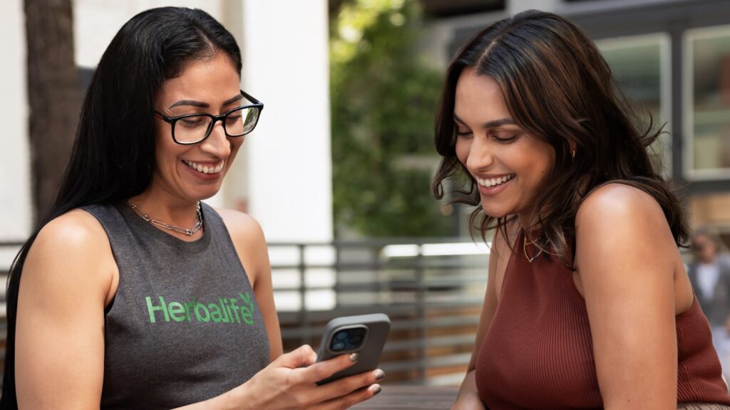 Deux femmes souriantes découvrant Herbalife sur smartphone – Shop-Nutriform